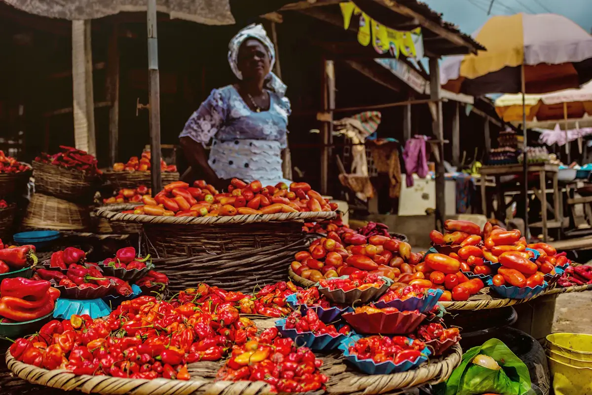 Une vendeuse au milieu de paniers de piments et de tomates sur un marché